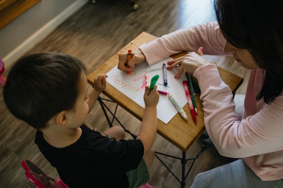 A teacher and child writing together