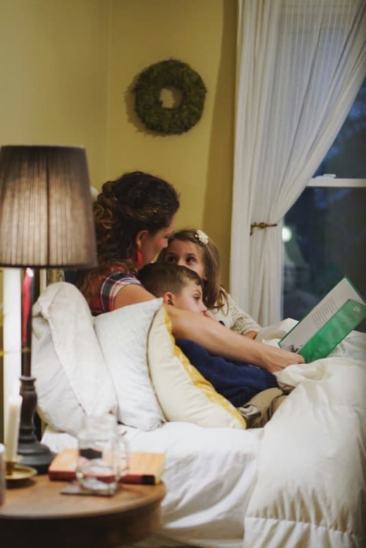 A parent reading with two children at home